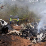 Kenyan security officials secure the wreckage of an aircraft which crashed with 11 people onboard.