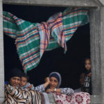 Palestinian women and children look out from a window after US President Donald Trump announced that Israel and Hamas agreed on the first phase of a Gaza ceasefire, in central Gaza, 9 October 2025.